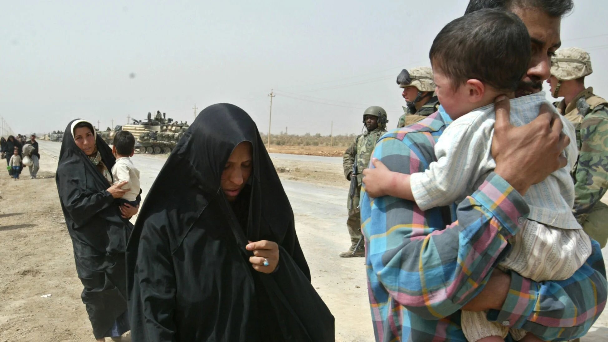 An Iraqi family, refugees from Baghdad, walk next to a US marine on the road south-east of the Iraqi capital April 5, 2003 (Reuters)