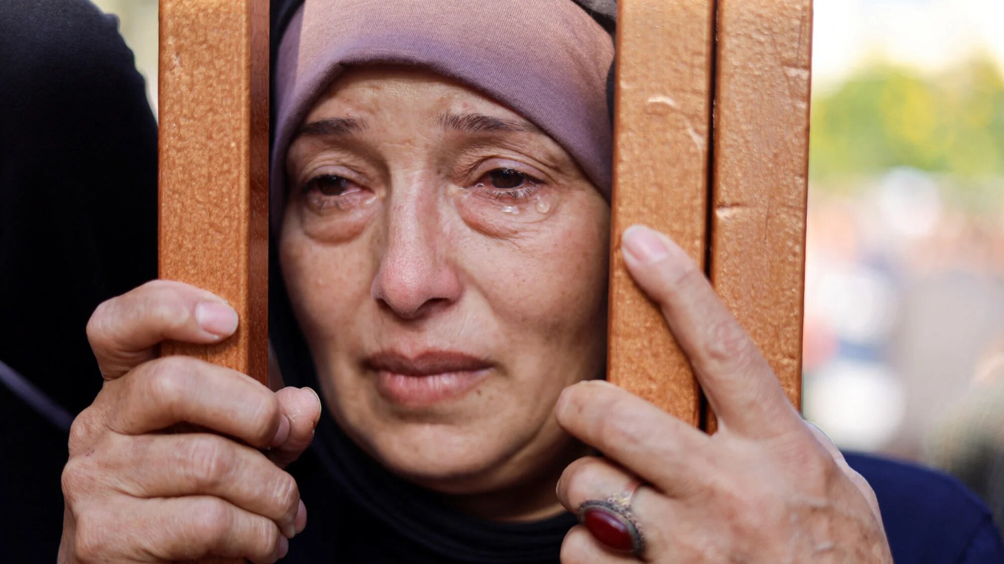 A woman looks on from behind a gate next to the bodies of Palestinians killed by Israeli strikes in Khan Younis in the southern Gaza Strip, 26 October 2023 (Reuters)