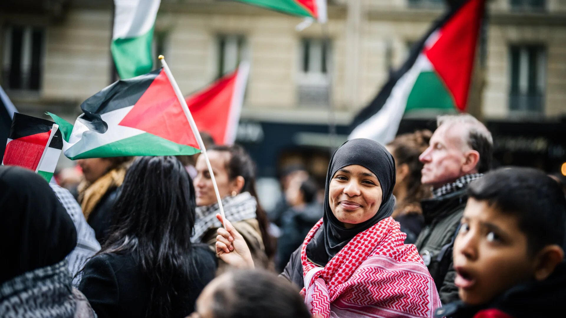 A young Muslim woman holding a Palestinian flag participates in an "against racism, against Islamophobia" march in Paris, France, on 21 April 2024 (Hans Lucas/Reuters)