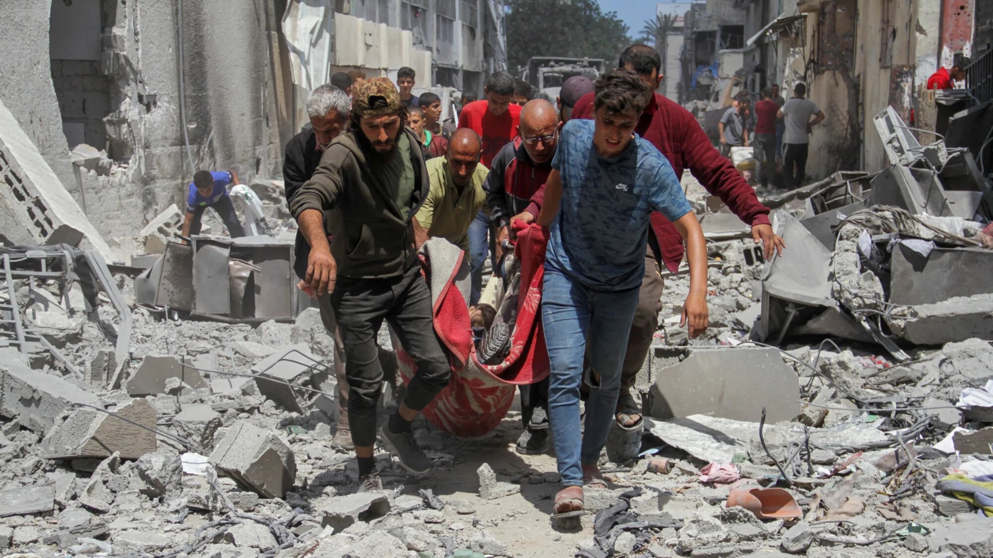 Palestinians carry the dead body of a man at Zeitoun neighborhood in Gaza City 15 May 2024 (Retuers/Mahmoud Issa)