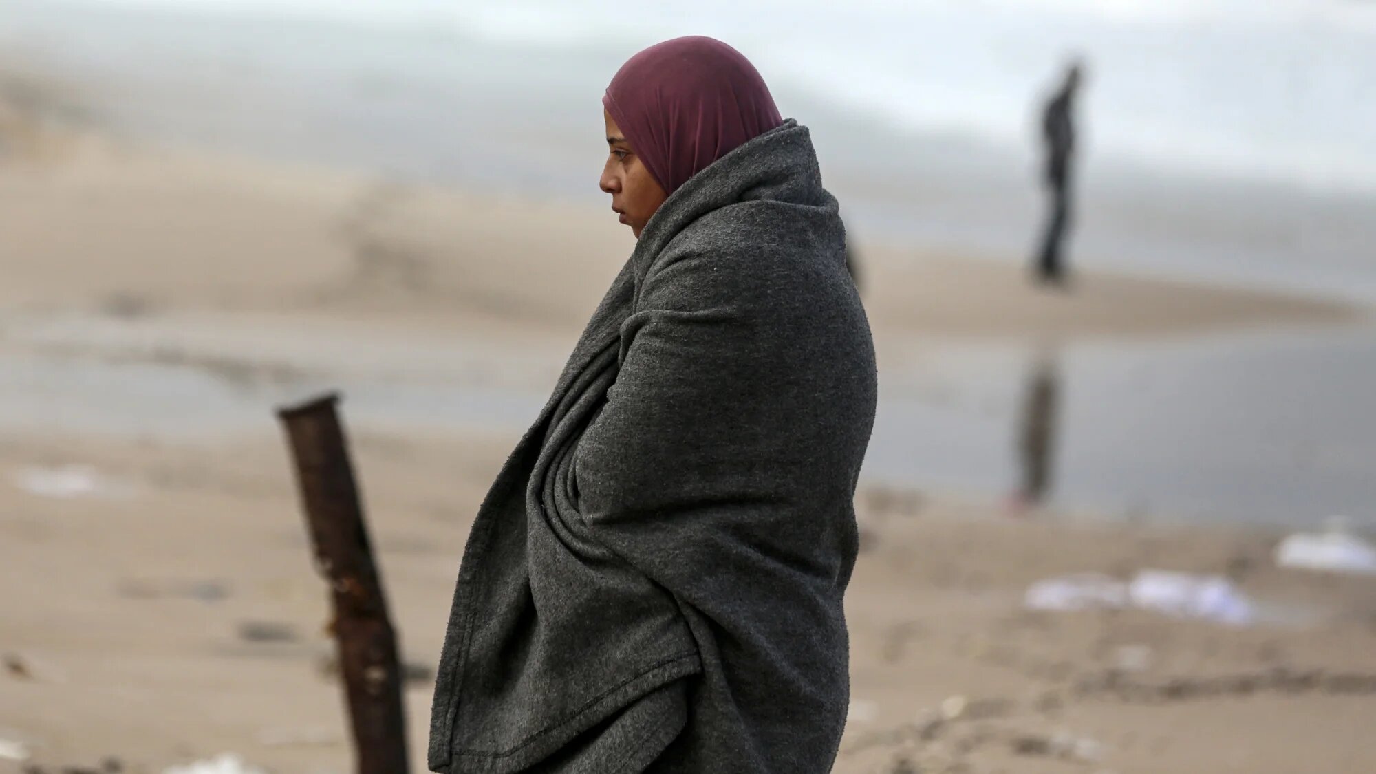 A displaced Palestinian woman stands outside her tent, which is damaged by wind and rain, in Deir al-Balah central Gaza Strip, on 25 November 2024(Majdi Fathi/NurPhoto via Reuters)