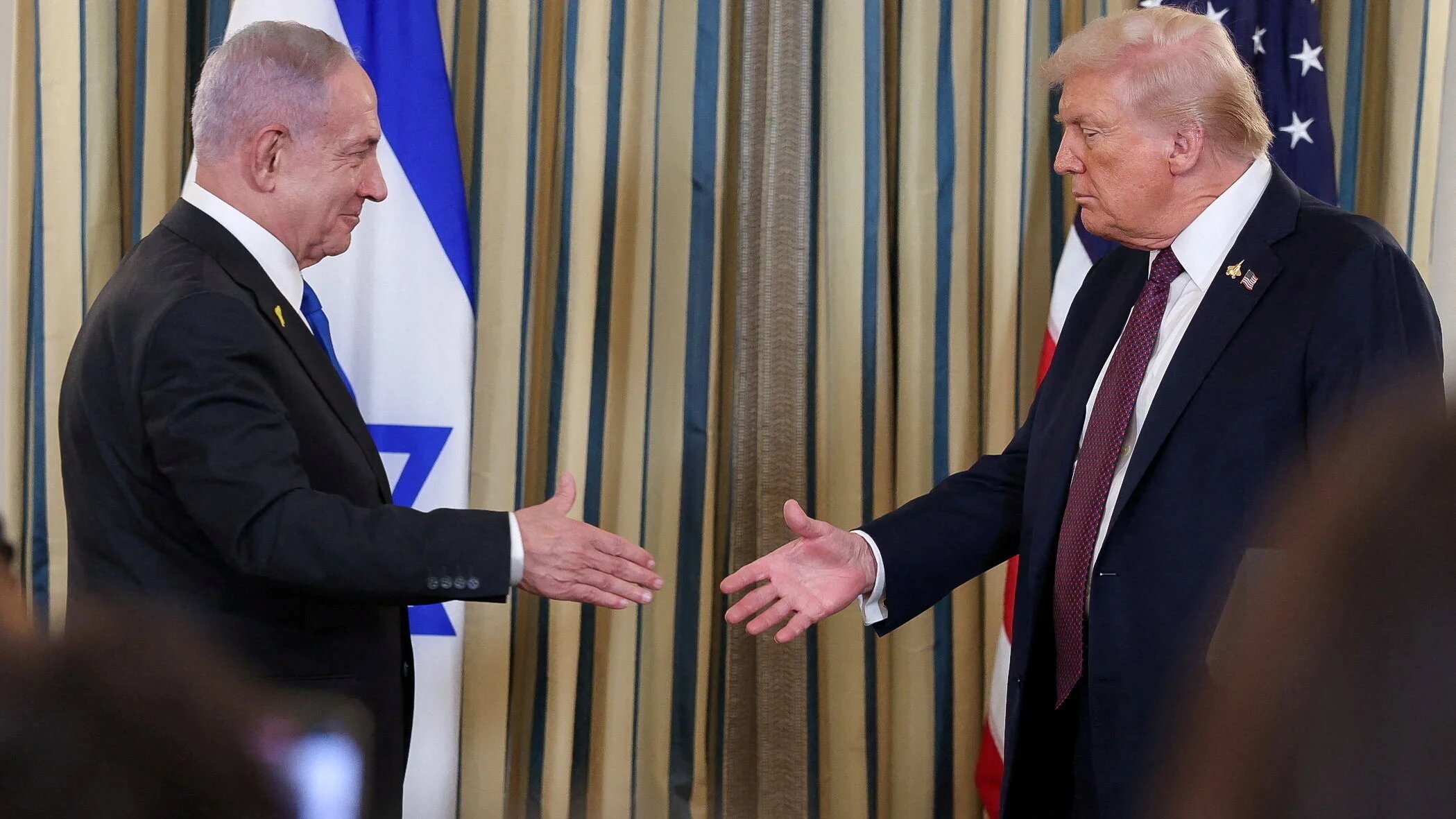 US President Donald Trump and Israeli Prime Minister Benjamin Netanyahu reach to shake hands at a joint press conference in Washington, on 29 September 2025 (Jonathan Ernst/Reuters)