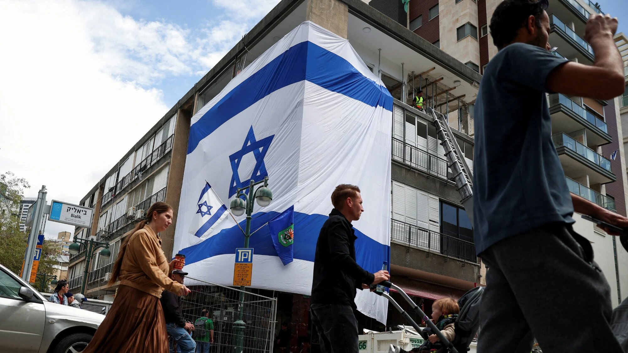 People pass by an impact site, which is wrapped in a large Israeli flag, in the aftermath of missile attacks launched from Iran into Israel on Monday on 7 April 2026 (Reuters/Florion Goga)