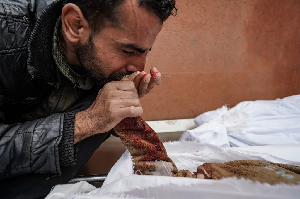 A Palestinian man mourns over the body of a relative killed in Israeli strike at the Nasser hospital in Khan Younis in the southern Gaza Strip on 28 December 2023 (AFP)