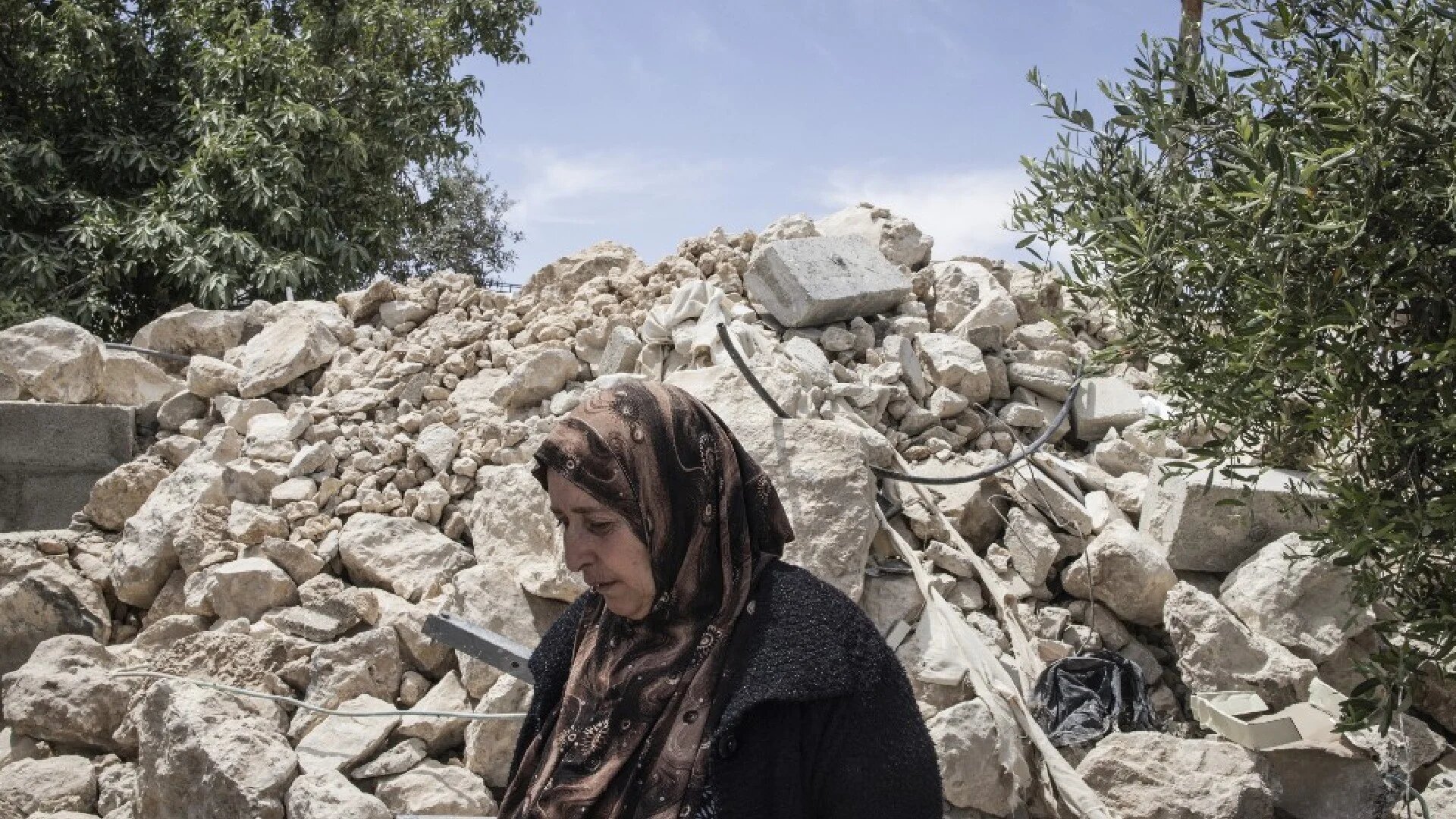 A Palestinian woman walks past a destroyed house in the village of Khallet al-Daba in the Masafer Yatta area in the occupied West Bank on 6 May 6 2025 (AFP)