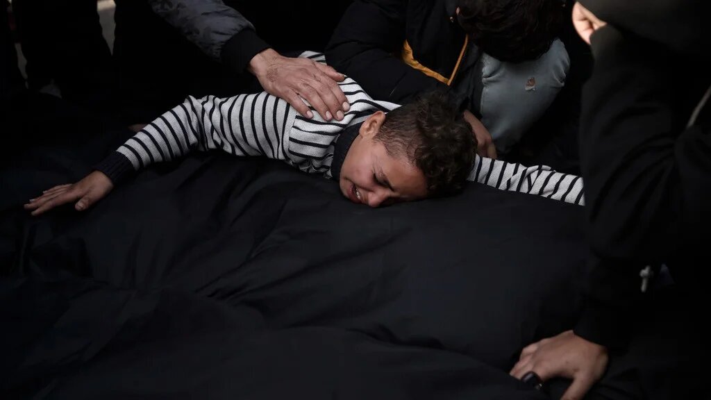 Palestinians mourn relatives killed in the Israeli bombardment of the Gaza Strip outside a morgue in Khan Younis on 20 December 2023 (AP)
