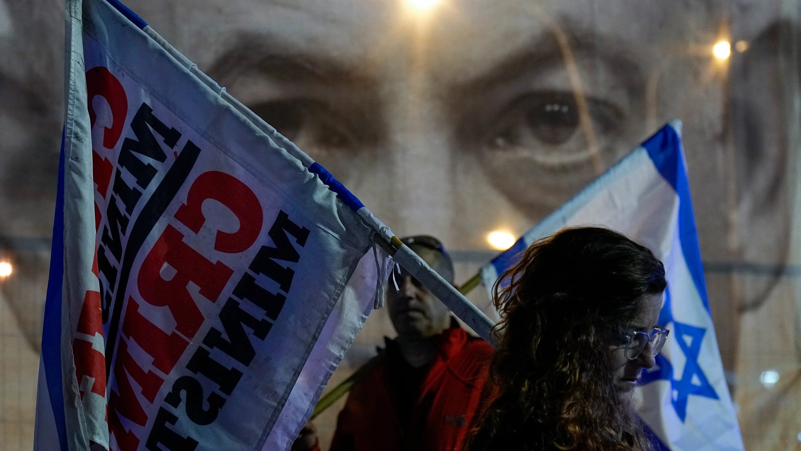 Israelis observe a moment of silence for victims of a shooting in Jerusalem in which seven people were killed by a Palestinian, at the beginning of an anti-government in Tel Aviv on 28 January 2023 (AP)