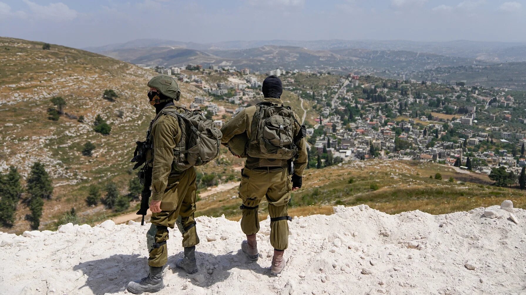 Israeli soldiers secure the construction site as Jewish settlers work at a seminary that was built overnight in the West Bank outpost of Homesh, on 29 May (AP)