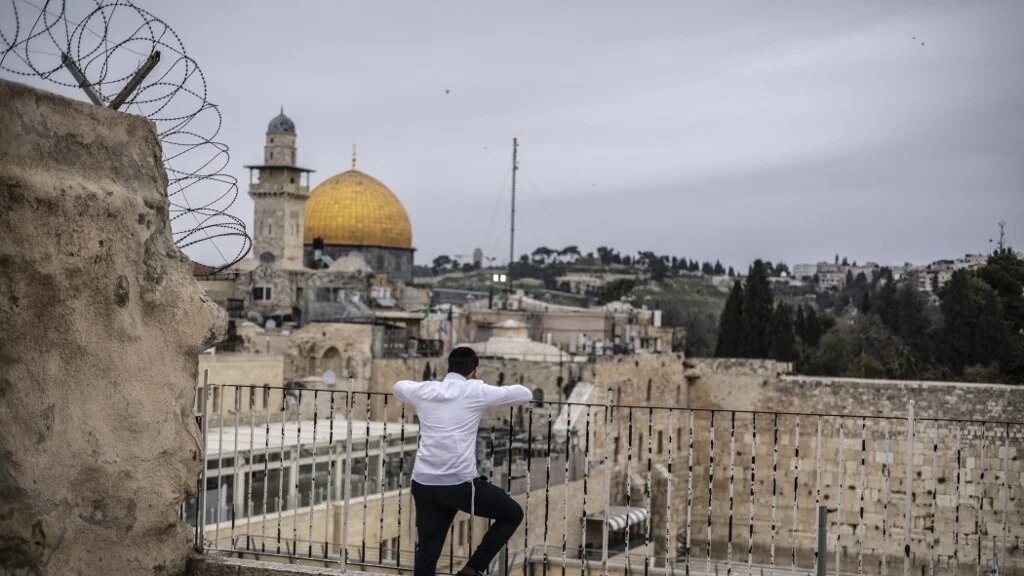 An ultra-Orthodox Jewish man prays in front of the closed Western Wall overlooking the Al-Aqsa Mosque complex in the Old city of Jerusalem on 13 March 2026 (Olympia De Maismont / AFP)