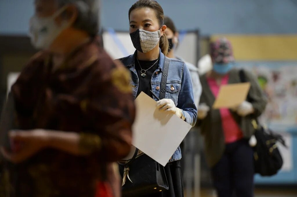 People wait in line to hand in their ballots to election officials after voting at a YMCA in Chinatown during the Massachusetts State Primary on 1 September in Boston