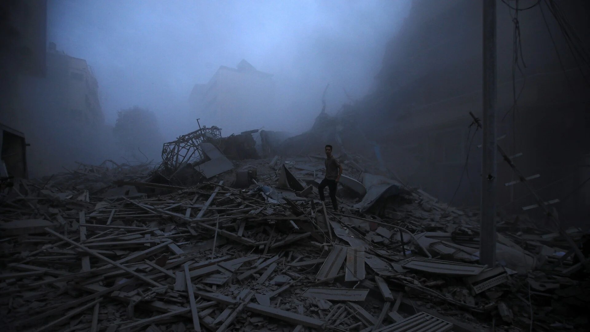 A man stands in the rubble of a destroyed Palestine Tower, Gaza City (MEE/Mohammed Zaanoun)