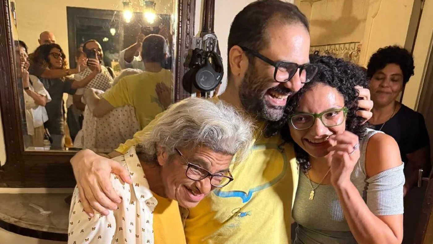 Alaa Abd el-Fattah, his mother Laila Soueif and sister Sanaa Seif embrace following his release on 22 September in Cairo (Supplied)