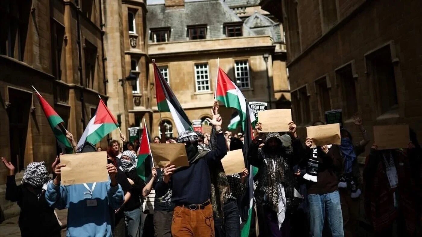 Students wave Palestinian flags during a protest at Cambridge University on 7 May 2024 (AFP)