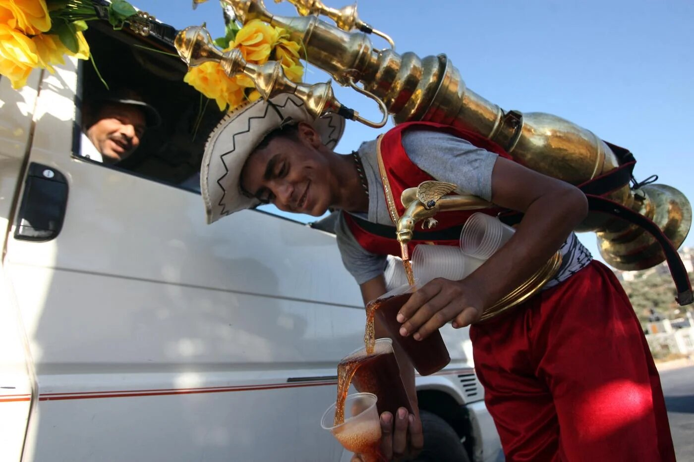 Un vendeur de rue palestinien propose du jus de caroube glacé dans la ville cisjorda-nienne de Ramallah (AFP/Abbas Momani)