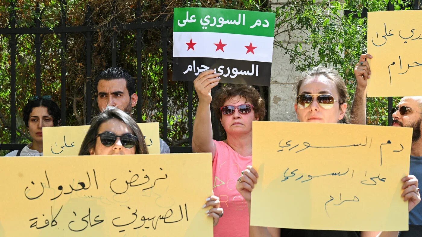 Syrians protest sectarian clashes and Israeli strikes, denouncing efforts to divide the country along ethnic and sectarian lines amid attacks in Sweida, outside parliament in Damascus on 16 July 2025 (Louai Beshara/AFP)