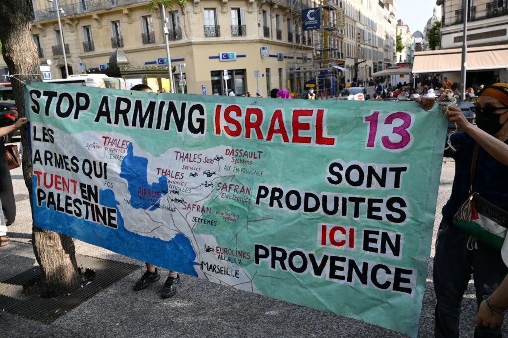 Demonstrators install a banner reading "The weapons killing in Palestine are produced here in Provence" at a gathering against a shipment of Eurolink military equipment parts set to go to Israel, in Marseille on 5 June (Christophe Simon/AFP)
