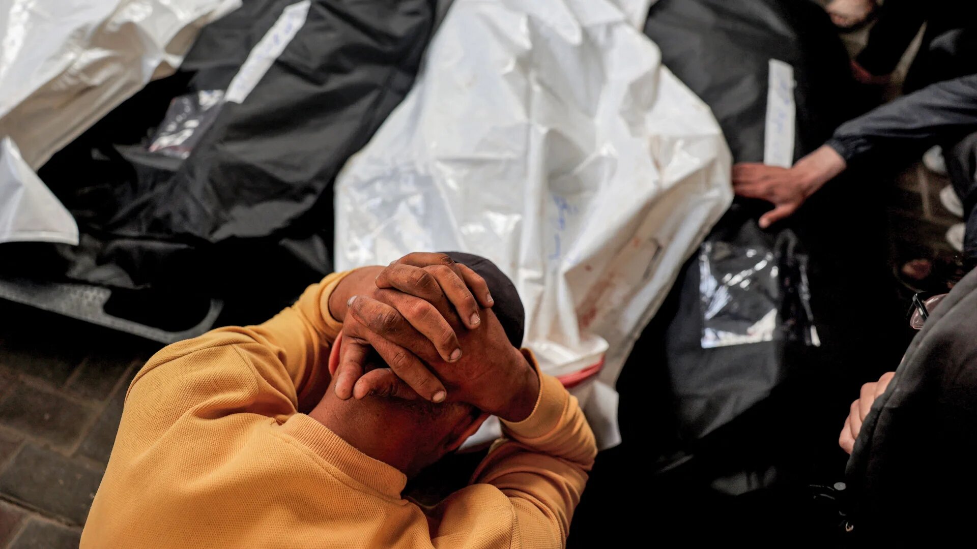 A Palestinian man mourns over the bodies of relatives who were killed the previous night during Israeli bombardment, at Al-Najjar hospital in Rafah in the southern Gaza Strip on 16 April (AFP)