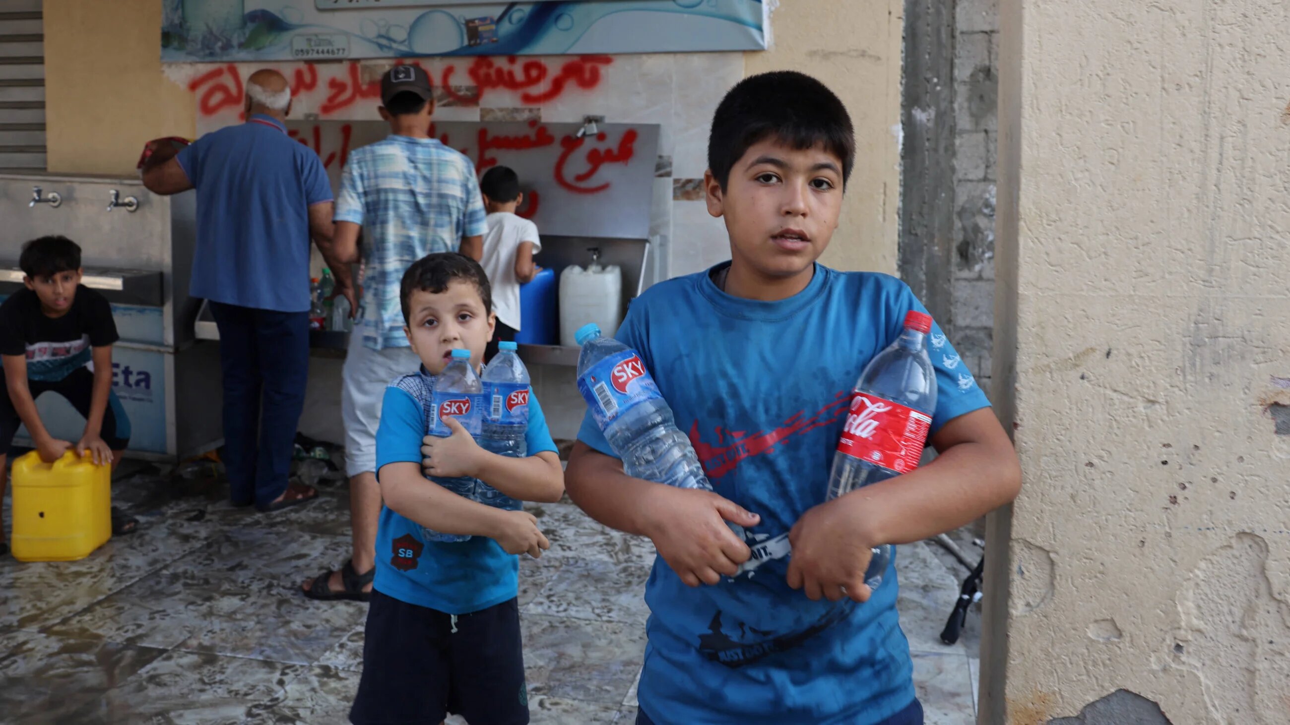 Children collect water from a public water collection point, as raging battles between Israel and the Hamas movement continue for the sixth consecutive day in Gaza City on 12 October 2023 (AFP)
