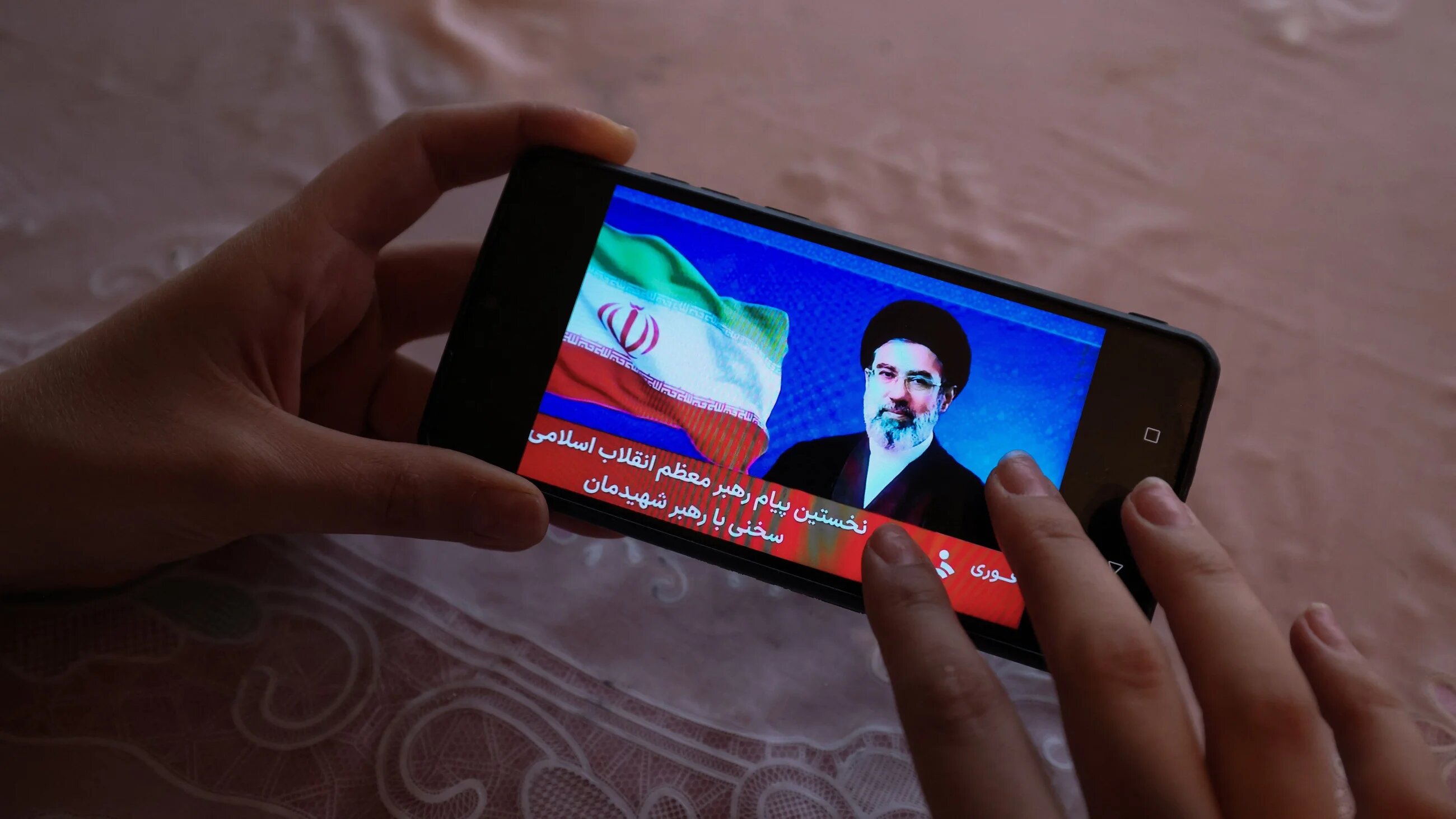 A girl watches a televised statement by Iran's new supreme leader Mojtaba Khamenei on a mobile phone on March 12, 2026 (AFP)