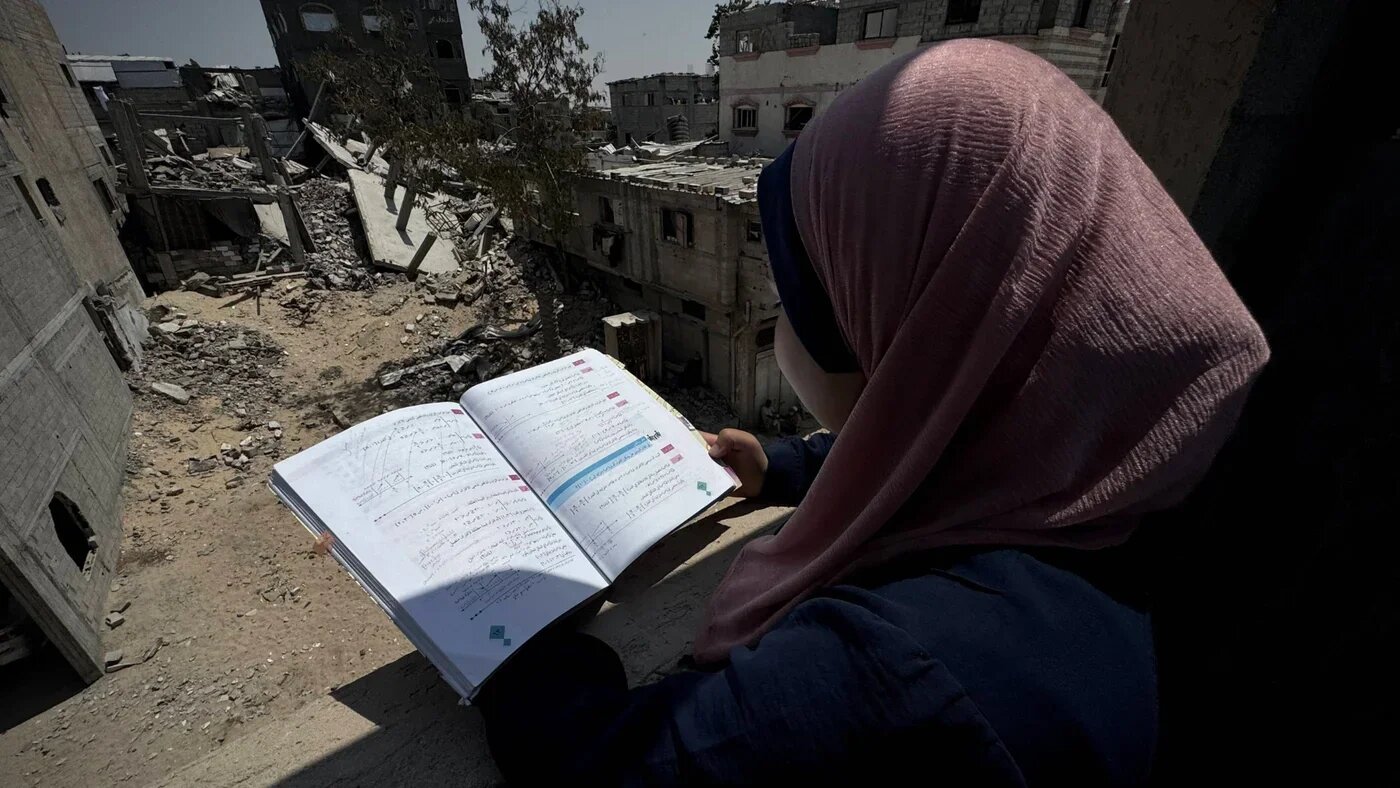 A Palestinian student studies inside a tent her family set up over the ruins of their home in Khan Younis, on 22 June 2025 (Reuters/IMAGO/APAimages)