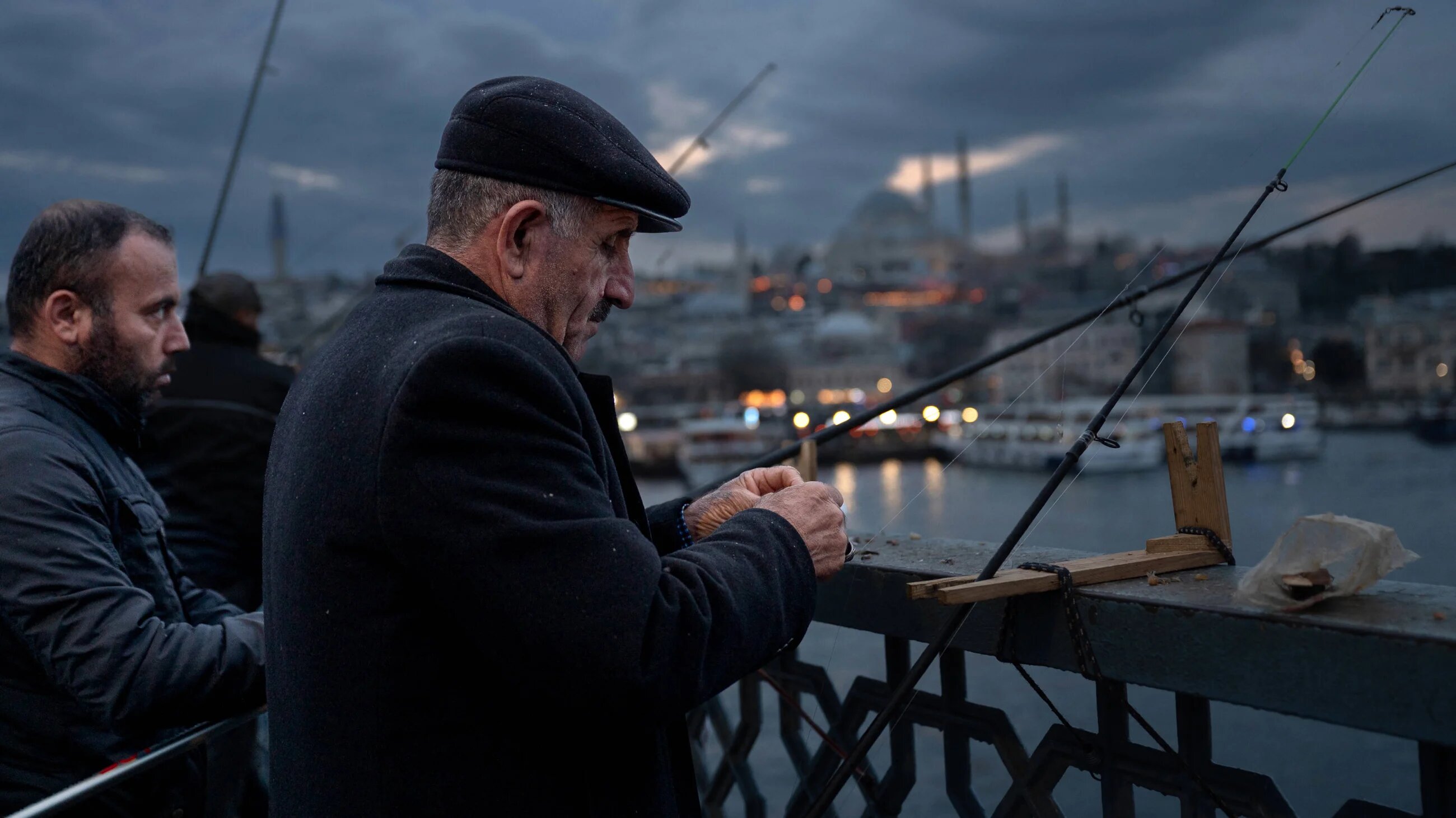Men stand on the Galata Bridge at sunset fishing not far from the Suleymaniye Mosque, in Istanbul on 7 January 2025 (AFP)