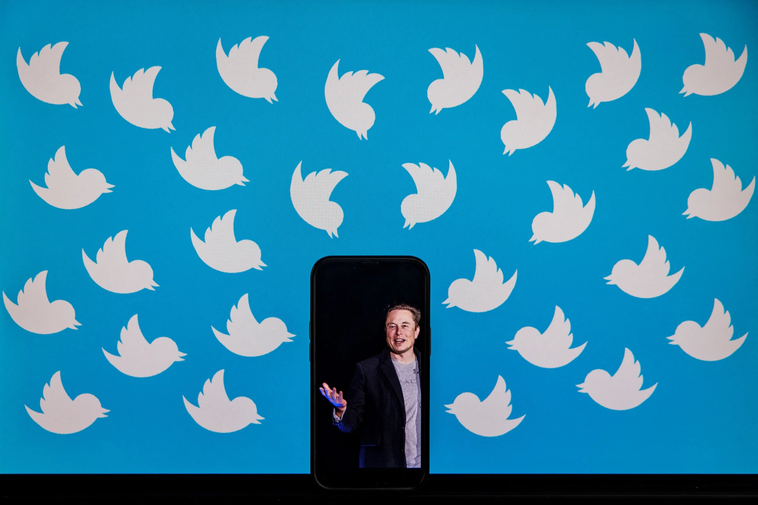In this file photo illustration taken on August 05, 2022, shows a cellphone displaying a photo of Elon Musk placed on a computer monitor filled with Twitter logos in Washington, DC.