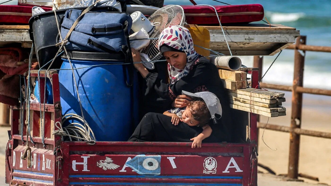 A woman and child in the back of a tricycle cart evacuating them southbound from Gaza City along the coastal road in Nuseirat, central Gaza on 9 September 2025 (AFP)