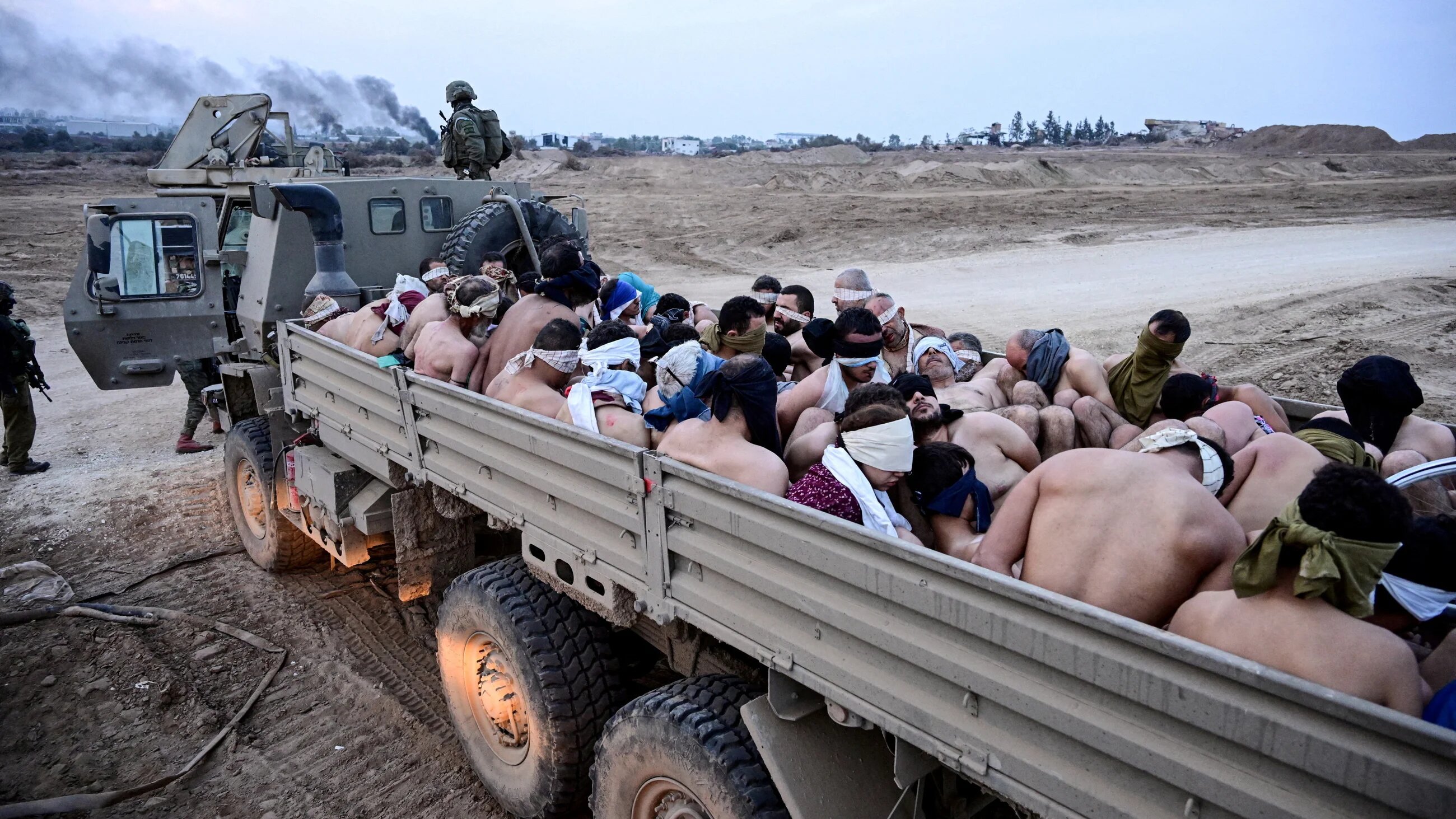 Israeli forces transfer blindfolded, stripped, and handcuffed Palestinian men arrested and detained, in the Gaza Strip, on 8 December 2023 (Yossi Zelige/Reuters)
