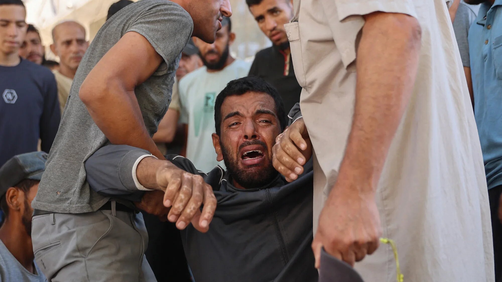 A Palestinian mourner cries during the funeral procession of people killed while waiting for aid, outside al-Shifa hospital in Gaza City on 3 July 2025 (AFP/Omar al-Qattaa)
