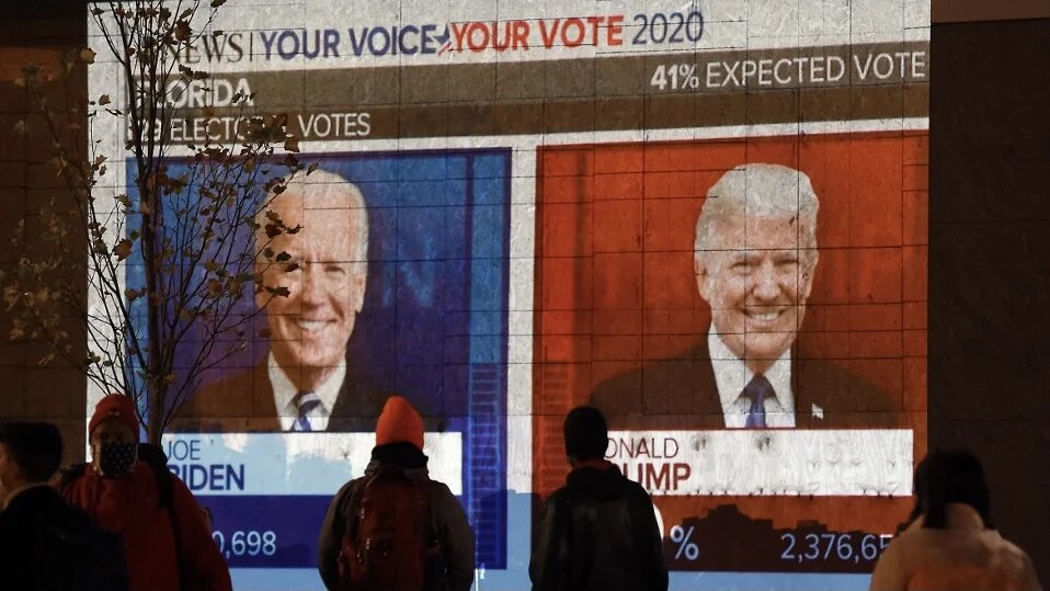 People watch a big screen displaying live US election results in Black Lives Matter plaza across from the White House, Washington, DC, 3 November 2020 (Olivier Douliery/AFP)