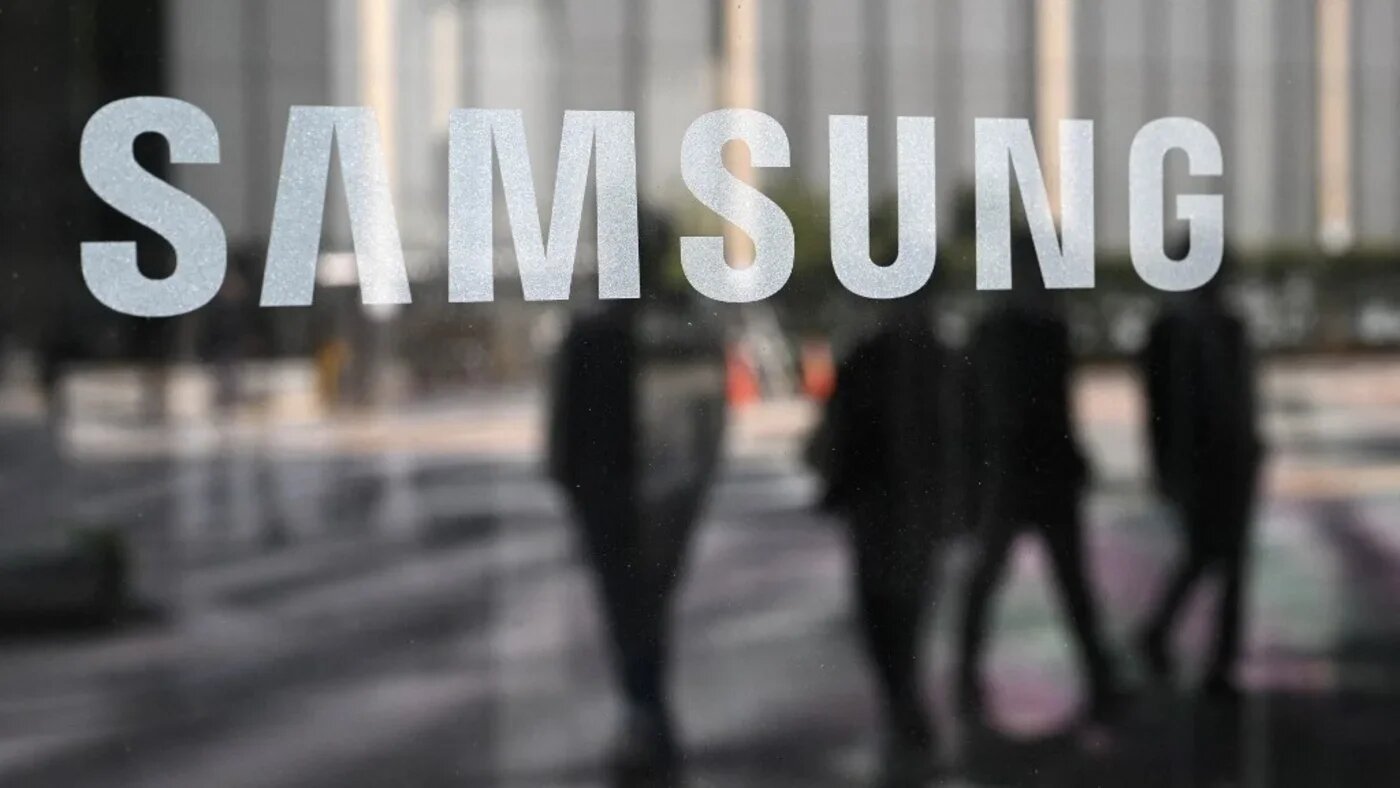People walk past the Samsung logo displayed on a glass door at the company's Seocho building in Seoul on 30 April 2025 (Jung Yeon-je/AFP)