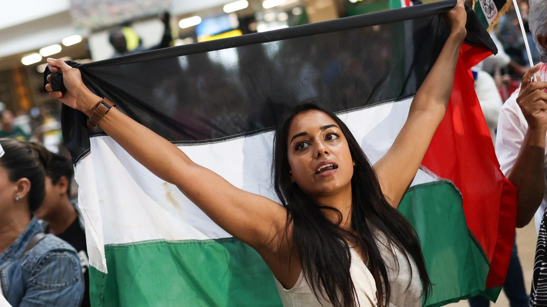 People gather in support of members of the South African legal team as they wait for them to arrive from The Hague, Netherlands, where they represented the country in a two-day hearing against Israel at the International Court of Justice (ICJ), 14 January 2023 (AFP)