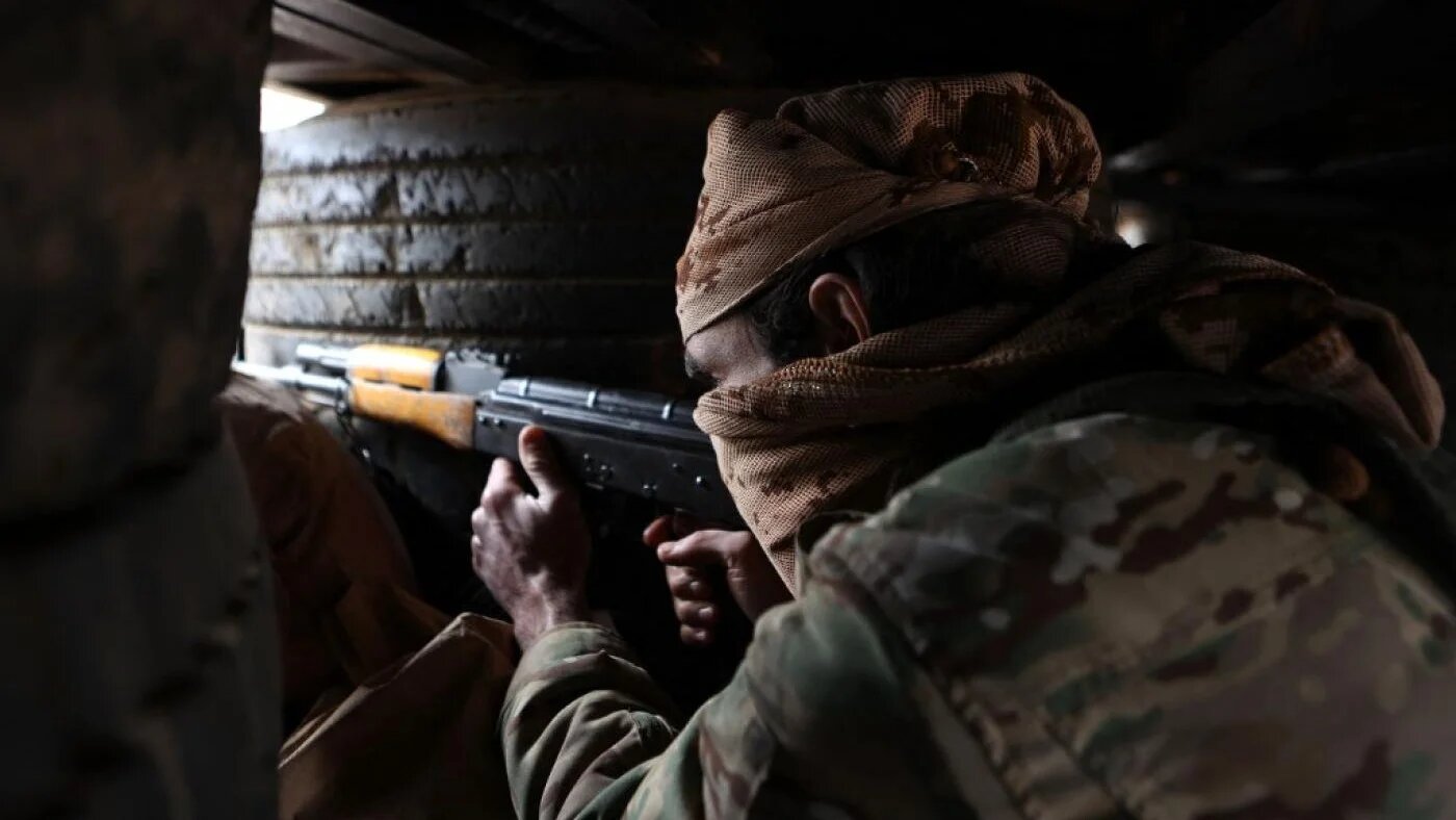 A rebel fighter takes aim from a murder hole in a make-shift fortified position near Azaz along the frontlines with areas under control by Syrian government forces and the Syrian Democratic Forces (SDF), on 26 November (AFP)