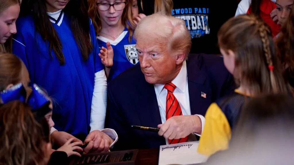 US President Donald Trump hands out pens to girls after signing the "No Men in Women's Sports" executive order in White House on 5 February 2025 in Washington, DC (AFP)