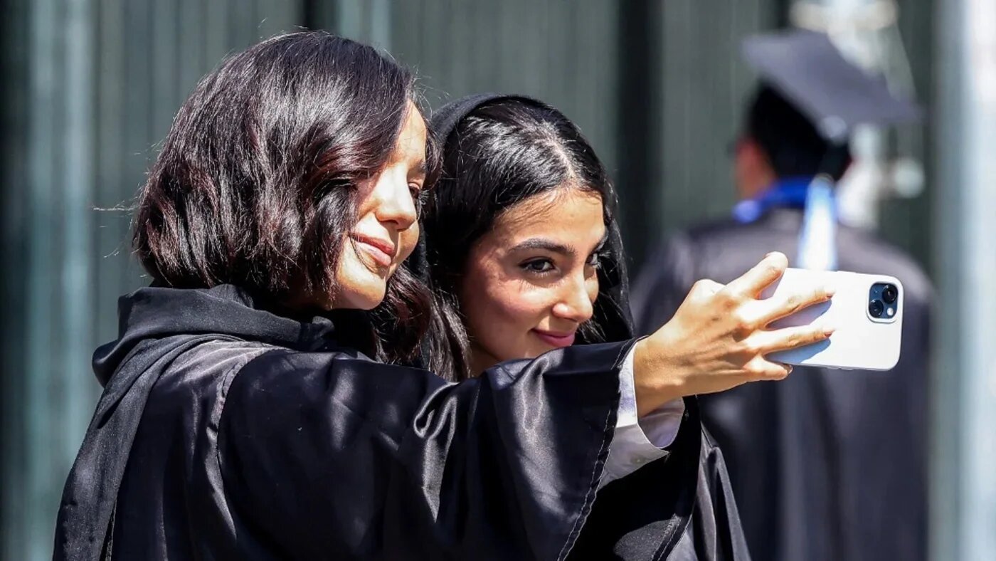 Students attending a graduation ceremony pose for a "selfie" at the University of Tehran on 15 September 2025 (Atta Kenare/AFP)