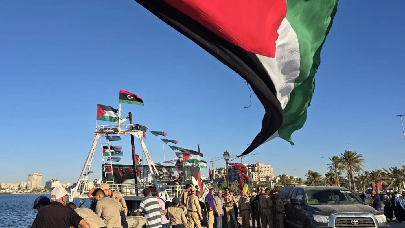 People pose for a picture in front of the Libyan Omar al-Mukhtar ship, part of the Global Sumud Flotilla, at the port in Tripoli on 16 September 2025 (Mahmud Turkia/AFP)