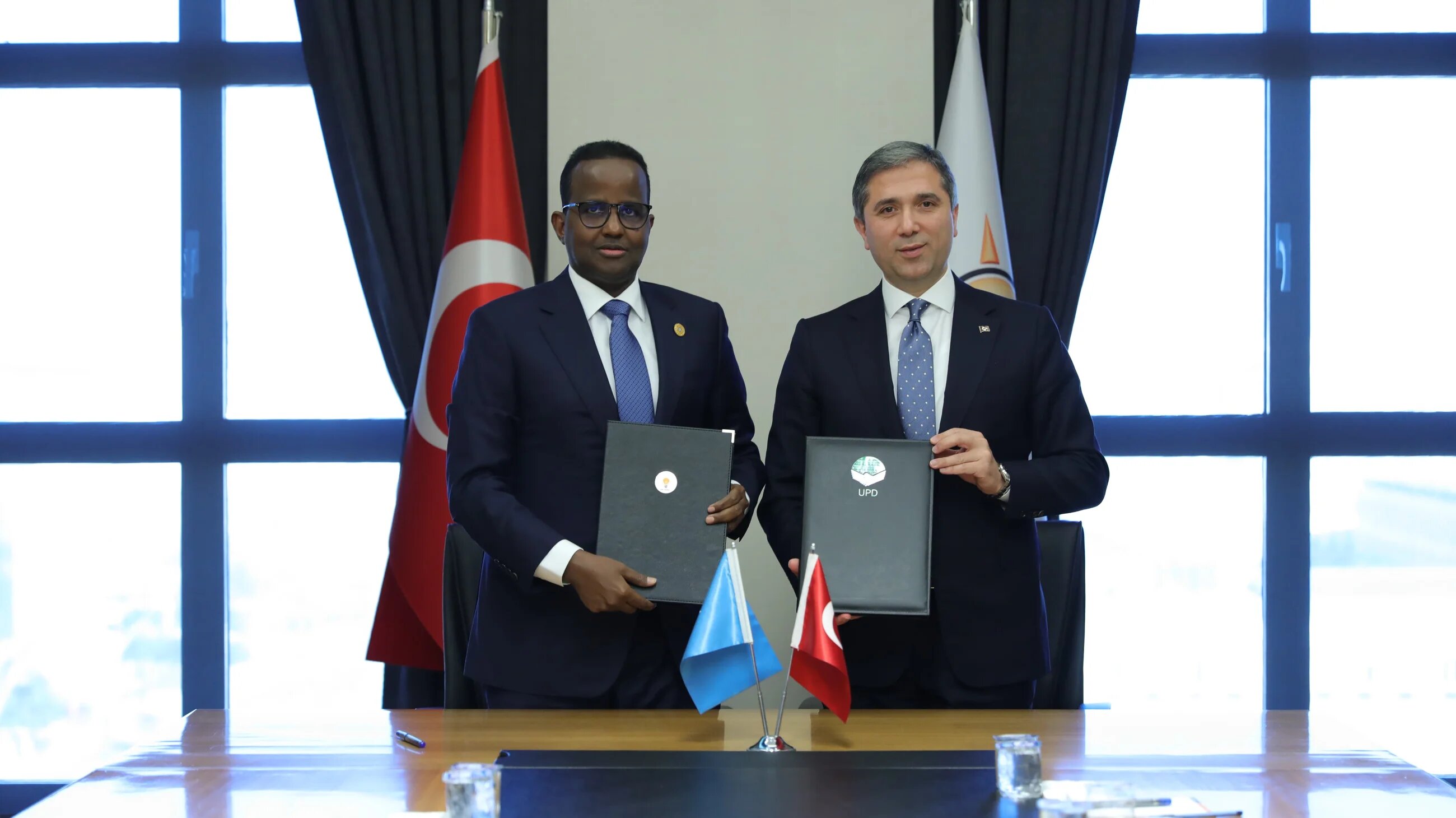 UPD Secretary-General Abdurahman Mohamed Hussein (L) and AKP Deputy Chairman Zafer Sirakaya sign a memorandum of understanding to establish close cooperation between the two ruling parties in Ankara on 29 January 2025 (Handout)