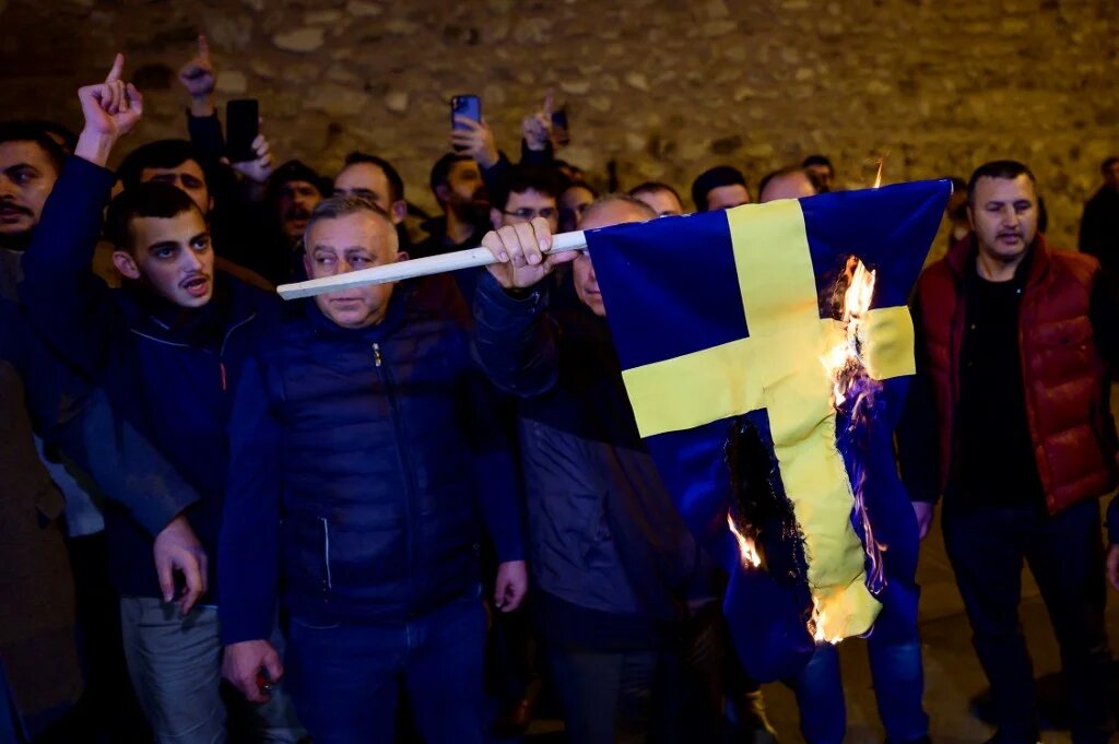 Protesters burn the national flag of Sweden as they demonstrate in front of the Consulate General of Sweden after Rasmus Paludan, leader of Danish far-right political party Hard Line and who also has Swedish citizenship burned a copy of the Koran near the Turkish Embassy in Stockholm, in Istanbul, on January 21, 2023. (AFP)