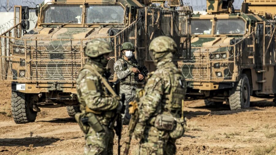 A Turkish soldier (C) looks on as he stands near Russian soldiers during a joint Russian-Turkish military patrol in the countryside near Syrian town Darbasiyah along the border with Turkey on 30 November 2020 (AFP)