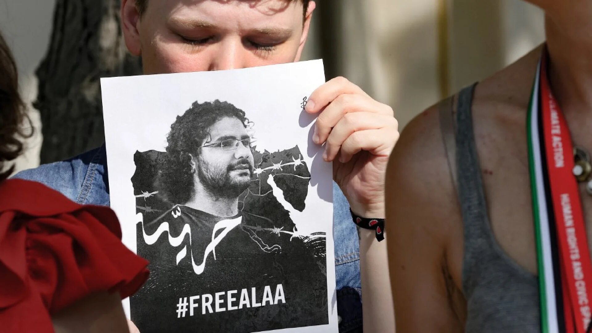 An protester holds a portrait of imprisoned Egyptian-British blogger Alaa Abd el-Fattah at the United Nations climate summit in Dubai on 9 December 2023 (AFP)