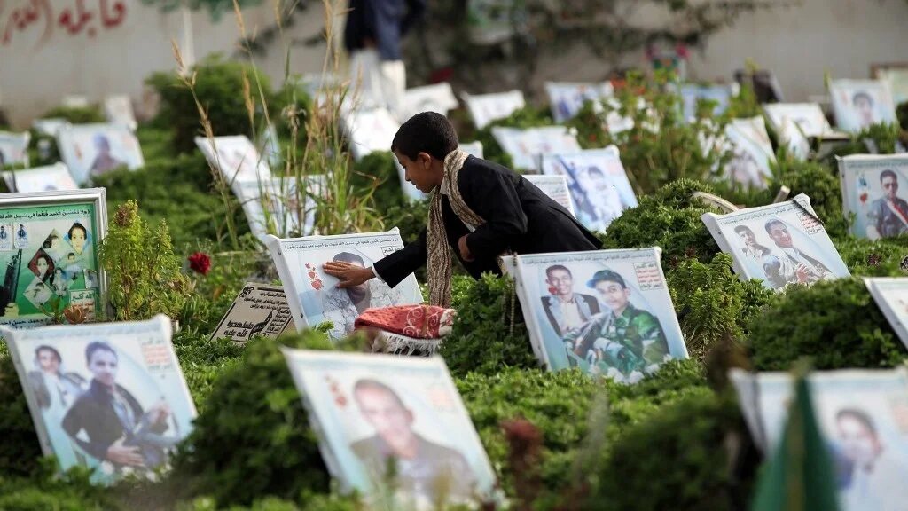 A boy prays at the grave of a relative in a cemetery in Yemen’s capital, Sanaa, in August 2019 (Mohammed Huwais/AFP)