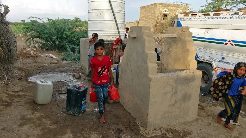 Yemeni children fill jerrycans with water at a makeshift camp for the internally displaced, in Yemen's war-ravaged western province of Hodeida on 7 May (AFP/File photo)