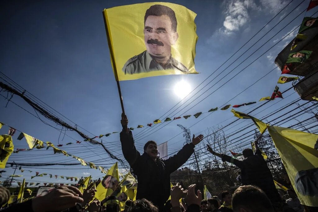 A protester waves a flag bearing a portrait of Abdullah Ocalan, the leader of the Kurdistan Worker's Party (PKK), during a demonstration in the city of Qamishli in northeastern Syria on 15 February 2025 (AFP/Delil Souleiman)
