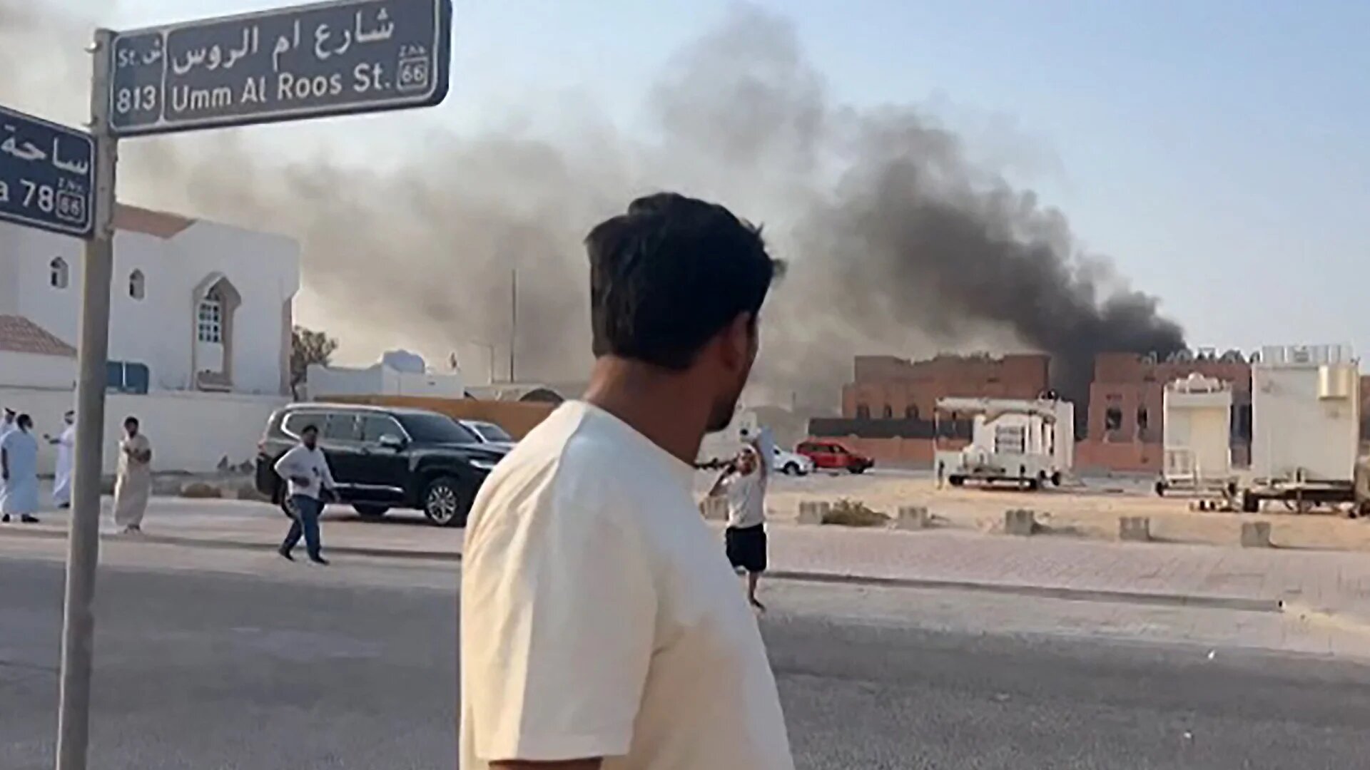 This frame grab taken from AFPTV footage shows a man looking at smoke billowing after explosions in Qatar's capital Doha on 9 September 2025 (AFP/Jacqueline Penney/AFTV)