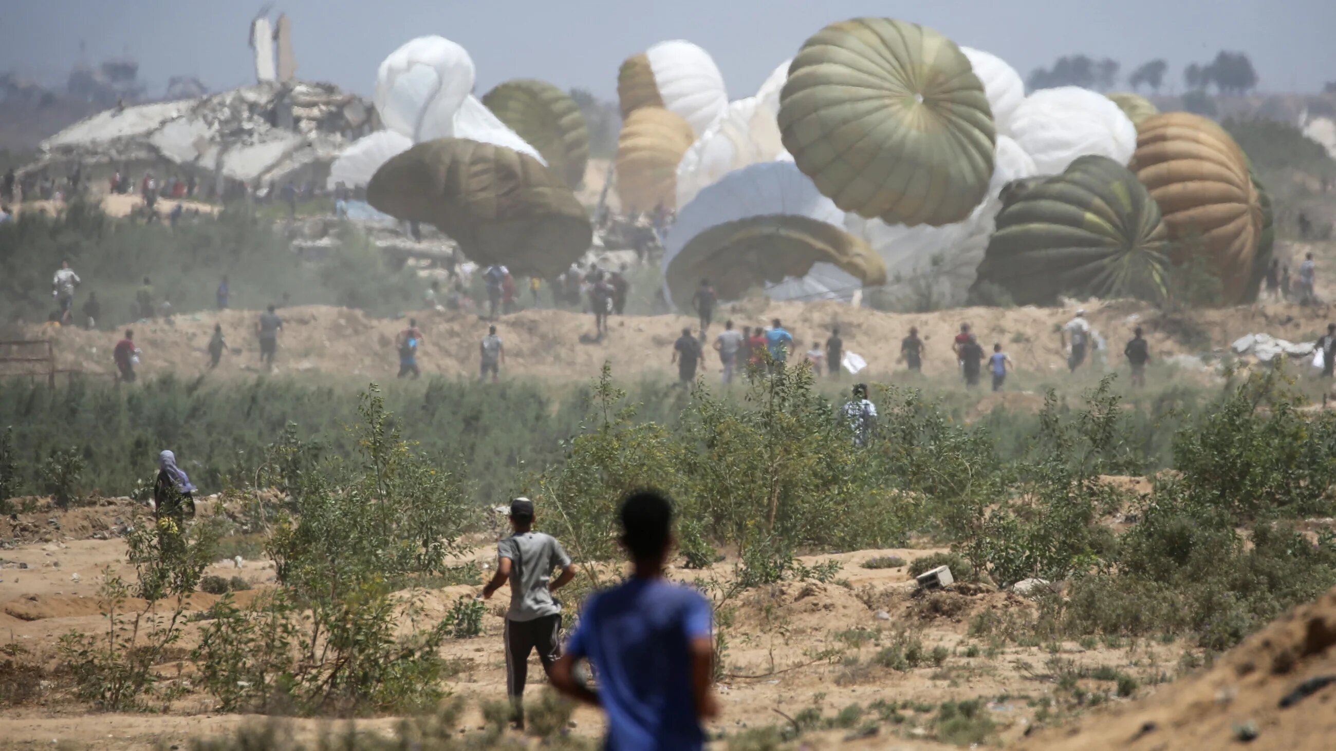 Palestinians rush to the site where parachuted aid packages land in the central Gaza Strip during an airdrop on 6 August, 2025 (AFP/Eyad Baba)
