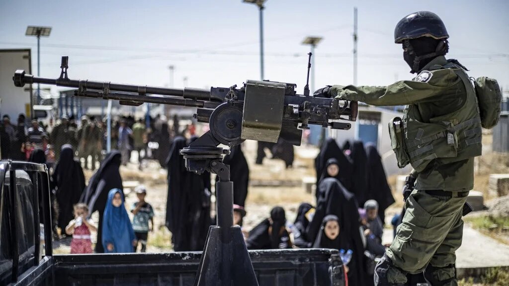 A member of the Kurdish security forces stands guard as released detainees prepare to leave al-Hol camp, northeastern Syria, 3 September 2023 (Delil Souleiman/AFP)