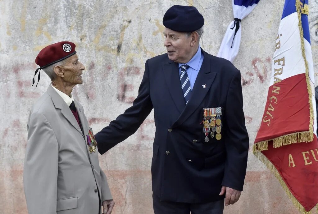 Deux harkis assistent à un rassemblement des harkis au camp de Rivesaltes pour alerter les politiques sur une loi de réparation, à l’occasion de la journée nationale de commémoration et de réflexion à la mémoire des victimes civiles et militaires de la guerre d’Algérie, soixante ans après la signature des accords d’Évian à Salses-le-Château, dans le sud de la France, le 19 mars 2019 (AFP/Raymond Roig)