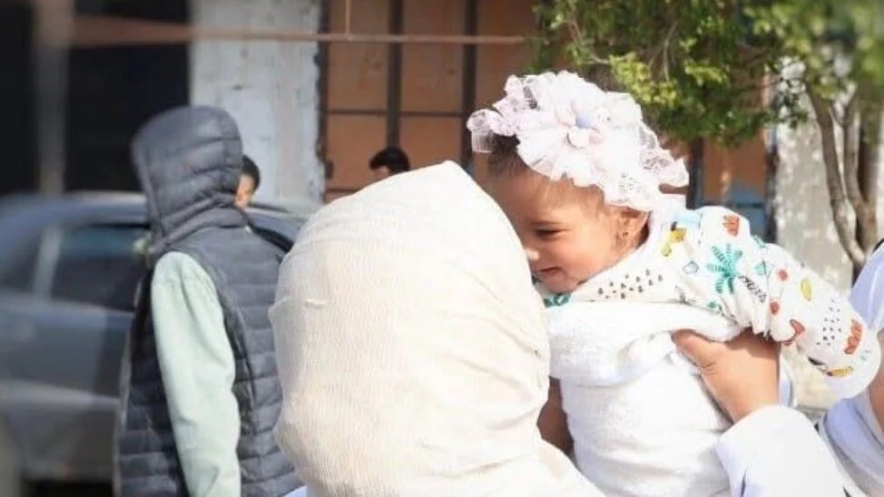 Palestinian nurse Amal Ismael carrying Malak, a girl whose parents have not been identified during the war on Gaza (Supplied)