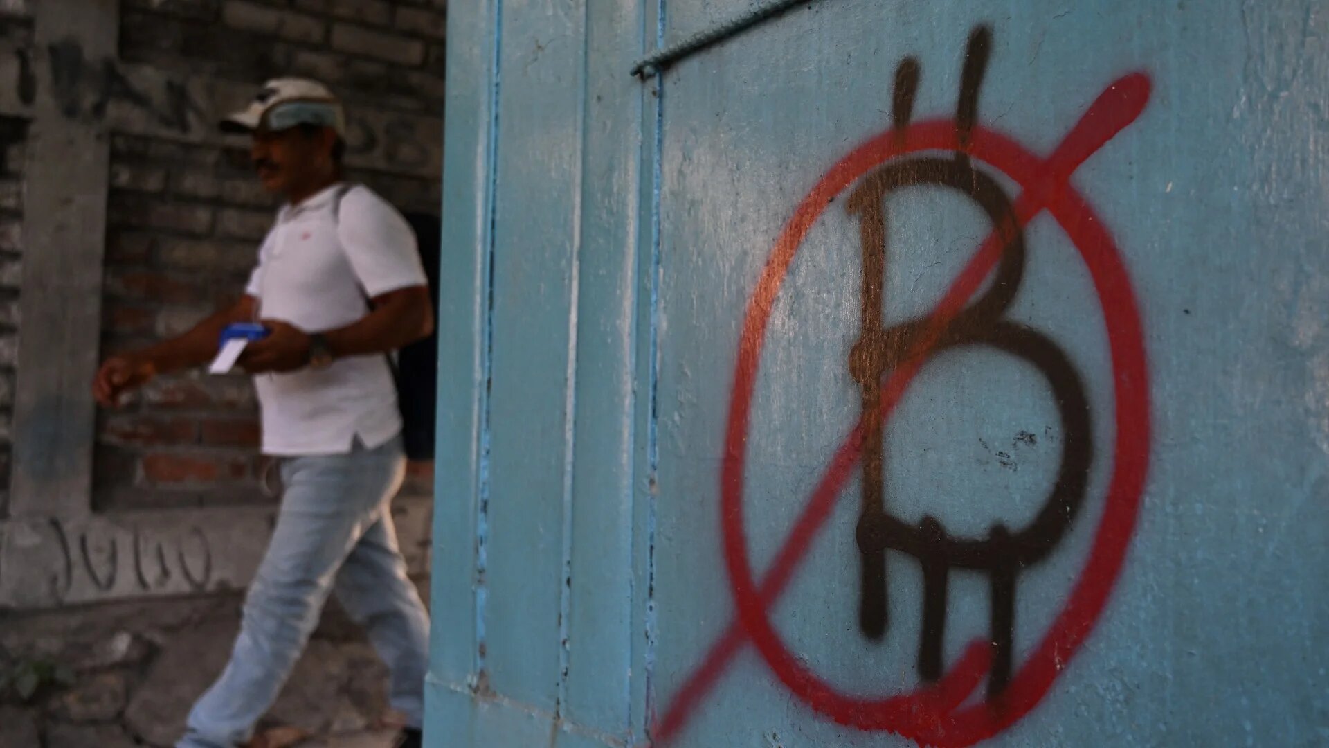 A man walks past a wall painted with an anti-bitcoin graffiti (AFP/File photo)