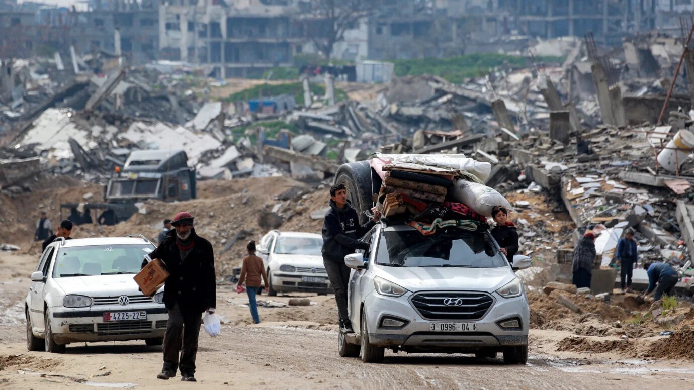 Boys ride outside a vehicle loaded with mattresses, blankets, and a giant cistern near Beit Lahia, northern Gaza on 11 February 2025 (Bashar Taleb/AFP)